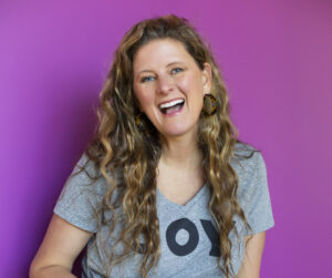 Sarah Laughing with Camera Purple Background