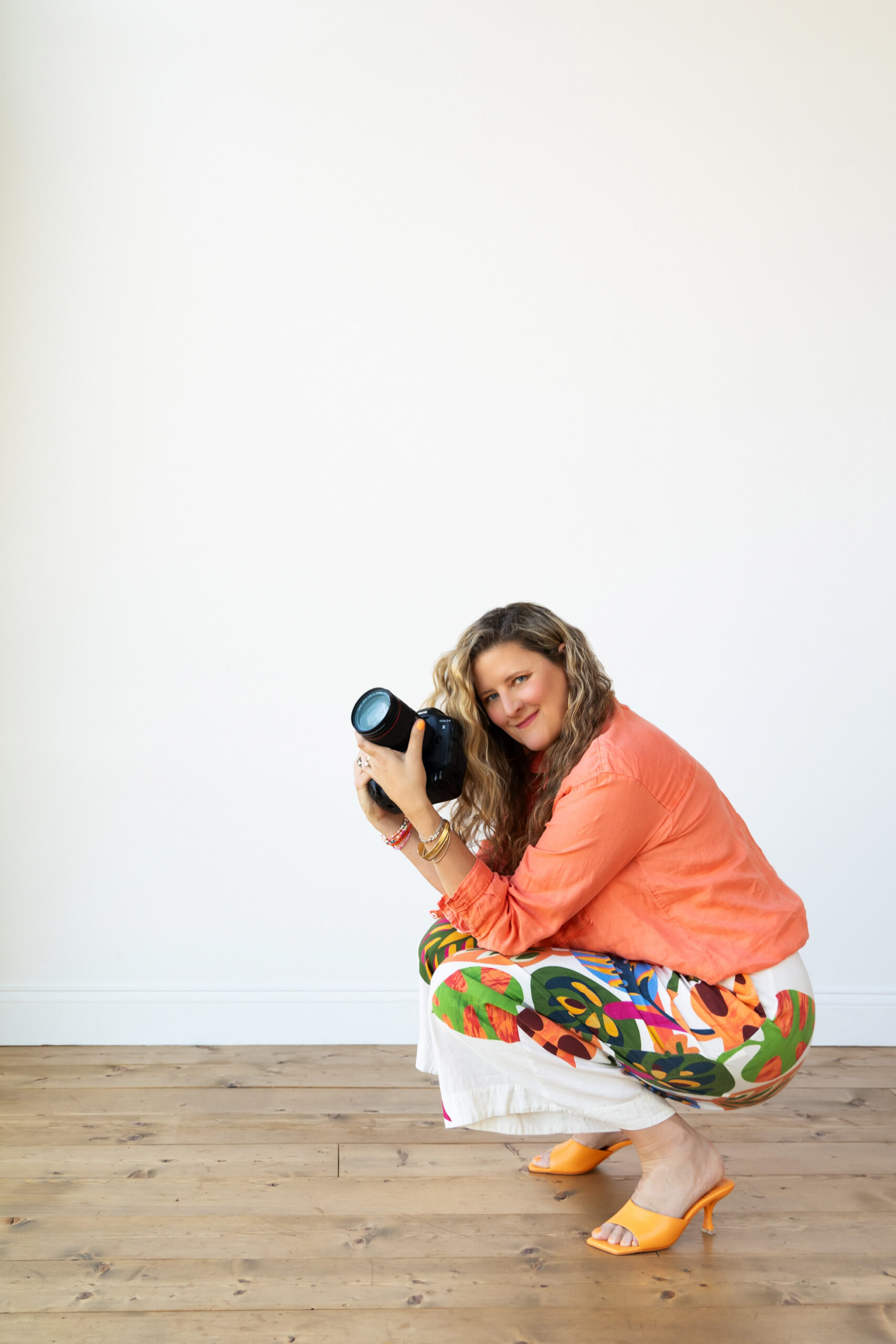 Sarah Petty Holding Camera White background crouching